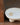 Gold Rosh sculptural ring on a white ceramic dish with a blurred background