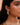 Close-up of a person wearing a gold earring with cascading leaves with a blurred background