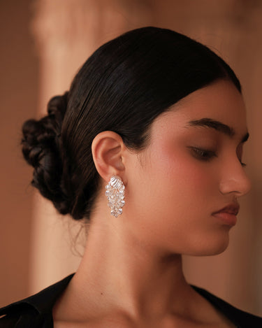 Close-up of a person wearing a silver earring with cascading leaves with a blurred background