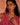 Woman wearing a pink top and gold jewelry against a peach background