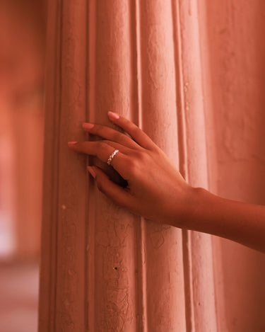 Hand with a ring on a textured pink surface