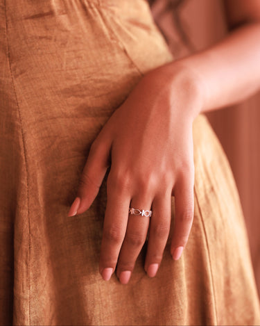 Close-up of a hand wearing a ring with a brown dress in the background